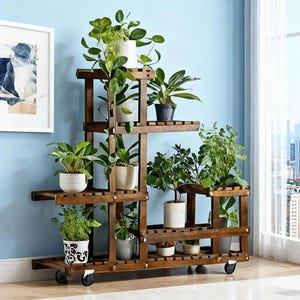 May include: A multi-tiered, dark brown wooden plant stand on wheels, filled with various potted green plants. The stand has multiple shelves of different sizes, creating a visually appealing display for indoor gardening. The background is a light blue wall.