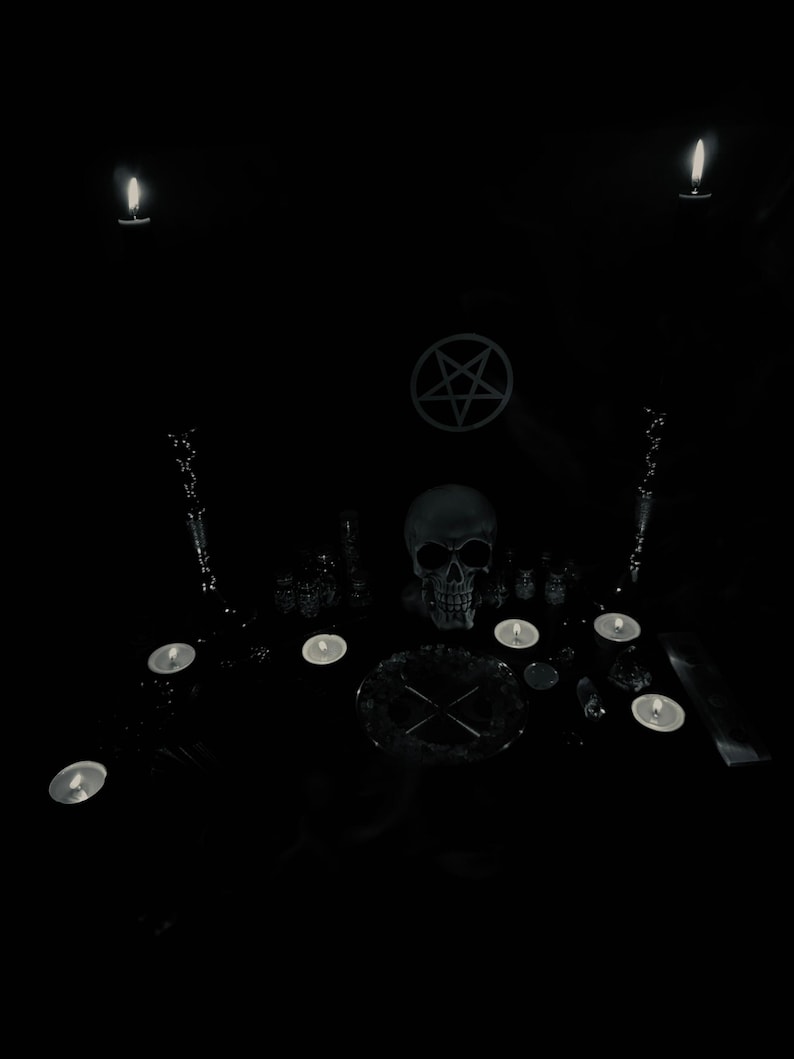 May include: A dark, moody scene featuring a human skull, lit candles, and a pentagram symbol. The arrangement includes various ritualistic objects, creating a gothic or occult aesthetic. The image is predominantly black and white.