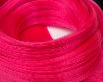 May include: Close-up of vibrant, hot pink hair extensions. The synthetic hair is tightly bundled, showcasing a smooth, silky texture. The bright color and close-up perspective highlight the product's vivid hue and potential for styling.