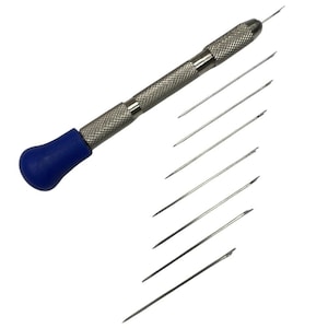 May include: A silver-toned needle holder with a textured grip and a blue end cap. Several silver needles are arranged beside the holder. This tool is likely used for sewing or crafting.