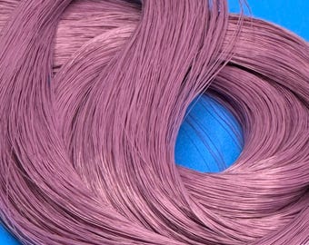 May include: A bundle of mauve-colored craft wire, tightly wound and secured with a white tie. The wire has a slightly shiny finish and is arranged in a circular shape against a blue background. This is a craft supply.