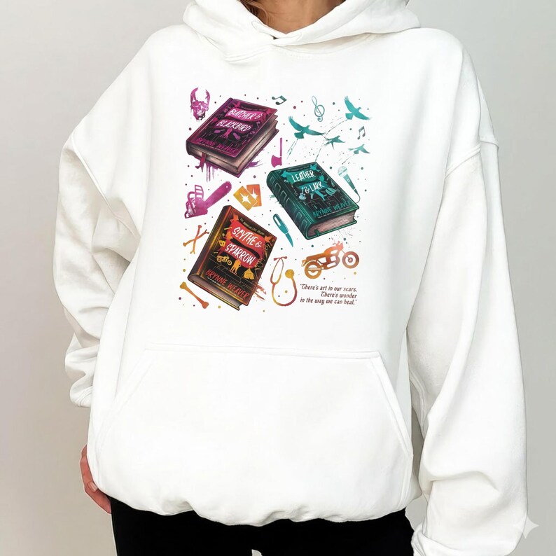 Butcher and Blackbird light pink sweatshirt with a vintage collage for the Ruinous Love series by Brynne Weaver. Detailed graphics of book covers for Leather and Lark and Scythe and Sparrow, featuring a skull, chainsaw, and motorcycle. Soft pastel pink crewneck pullover for dark romance readers.