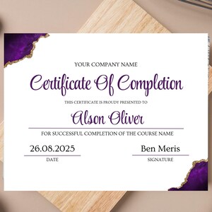 May include: A white certificate with purple and gold accents. The certificate reads "Certificate Of Completion" and includes the name "Alson Oliver" and the date "26.08.2025". The certificate is on a wooden surface.