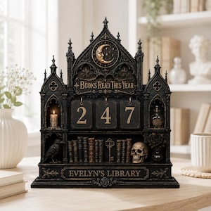 Puede incluir: Un expositor de libros de estilo gótico oscuro en madera con el texto 'BOOKS READ THIS YEAR' y 'EVELYN'S LIBRARY'. Incluye tres placas numéricas colgantes que muestran '247', una talla de luna creciente, un cuervo, una calavera y una llave.