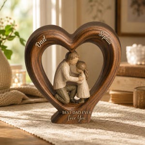 May include: A wooden heart-shaped sculpture with a father and daughter embracing inside. The sculpture is brown with the words "Dad" and "Sophia" inscribed on the heart. The base reads "Best Dad Ever Love You."