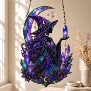 Puede incluir: Un atrapasoles de vidrieras con la silueta de una figura con sombrero de ala ancha y túnicas fluidas, sobre una luna creciente. El diseño incorpora tonos morados y azules intensos, múltiples estructuras cristalinas y estrellas colgantes.