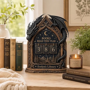 Puede incluir: Un expositor decorativo en forma de arco gótico con una escultura de dragón negro, que muestra el texto BOOKS READ THIS YEAR y Evelyn's Library, con tres placas numéricas colgantes que indican 386 sobre un fondo de noche estrellada.