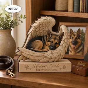 May include: A wooden memorial plaque featuring a German Shepherd dog sleeping within a pair of carved angel wings. The base is engraved with the text "Forever loved, forever missed" and paw prints, while the wing section displays the name "Max".