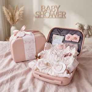 May include: A pink suitcase-shaped baby gift set with a matching bow and tag. The open suitcase reveals baby clothes, a card, and accessories. The set is decorated with butterfly motifs and the words "Baby Shower".