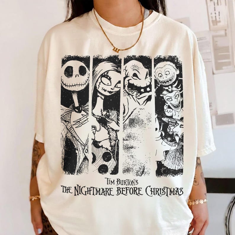 May include: A cream-colored short-sleeve t-shirt featuring a black graphic print of characters from Tim Burton's The Nightmare Before Christmas. The design includes four vertical panels displaying Jack Skellington, Sally, Oogie Boogie, and Lock, Shock, and Barrel.
