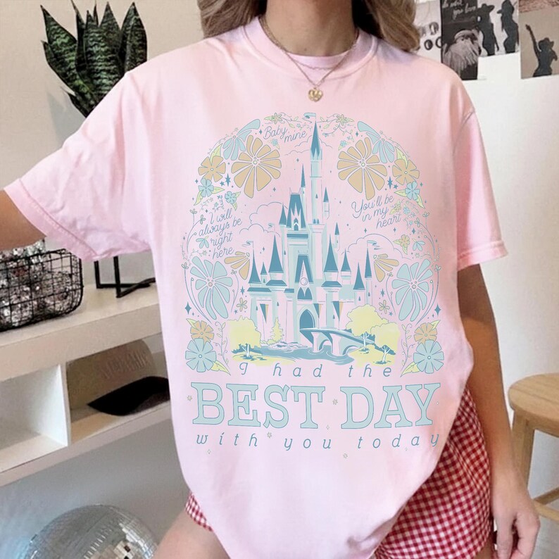 May include: A light pink t-shirt featuring a whimsical castle design with floral accents in pastel colors. The text "I had the BEST DAY with you today" is prominently displayed. Additional text includes "Baby mine", "You'll be in my heart", and "I will always be right here".