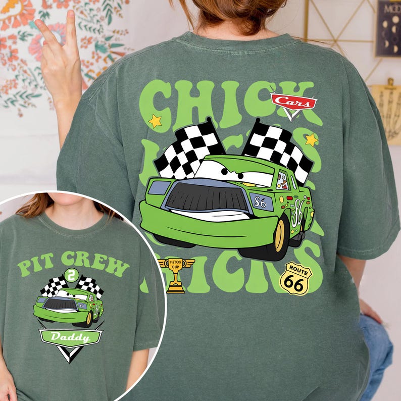 May include: Green t-shirt with a cartoon car design, the text "Chicks" and "Cars". The design includes checkered flags, stars, and the number "86". A smaller image shows a similar design with "Pit Crew" and "Daddy".