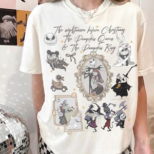 May include: A cream-coloured t-shirt with a design from "The Nightmare Before Christmas." The graphic includes Jack Skellington, Sally, and other characters, with the text "The Nightmare Before Christmas & The Pumpkin Queen & The Pumpkin King."
