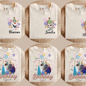 Puede incluir: Camisetas de color crema con gr&aacute;ficos de dibujos animados coloridos de personajes y texto de la pel&iacute;cula Frozen. Los dise&ntilde;os incluyen a Olaf, Elsa, Anna y texto con tem&aacute;tica de cumplea&ntilde;os. Cada camiseta est&aacute; doblada sobre una estera tejida.
