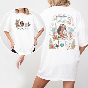 May include: White t-shirt with a vibrant graphic inspired by an animated film. The front features the text "How far I'll go" and character illustrations. The back displays the text "The Ocean Chose You" with a framed character illustration and other graphics.