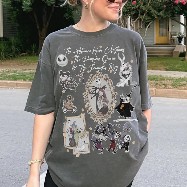 May include: Dark grey t-shirt with a graphic design featuring characters from "The Nightmare Before Christmas." The design includes Jack Skellington, Sally, and other characters. The text reads "The Nightmare Before Christmas & The Pumpkin Queen & The Pumpkin King."