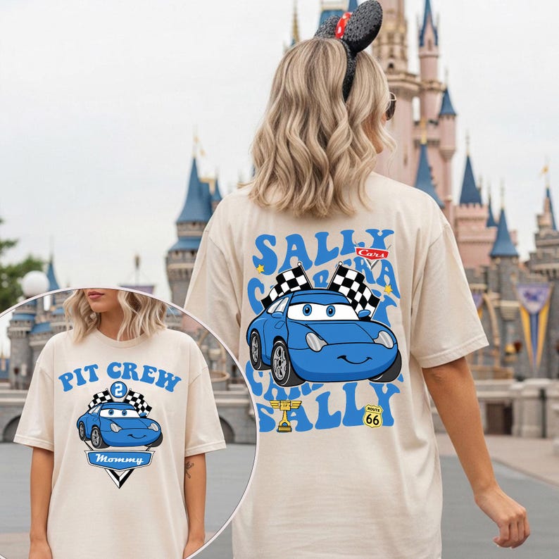 May include: Beige t-shirt with a blue cartoon car design, the text "Sally Cars", and checkered flags. The shirt also features "Route 66". A second shirt in the image says "Pit Crew" and "Mommy".