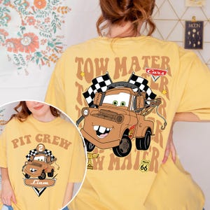 May include: Yellow t-shirt with a cartoon image of Tow Mater from the Cars film, with the text "Tow Mater" and chequered flags. The shirt also has the Route 66 logo and a smaller image of Mater on the front.