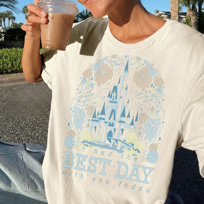 May include: Cream-colored t-shirt featuring a light blue castle design with floral accents and the text "I had the BEST DAY with you today." The design includes the phrases "Baby mine," "You'll be in my heart," and "I will always be right here."