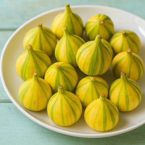 May include: A dozen ripe figs arranged on a white plate. The figs are yellow with green stripes, and have a small stem. The plate is on a light blue wooden surface. The figs are a fresh and healthy food.