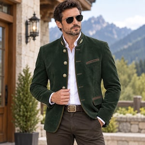 May include: A dark green suede blazer featuring a stand-up collar with gold embroidery, a white button-down shirt, and a brown belt with a decorative buckle. The blazer has metallic buttons and brown piping along the pockets and front edges.