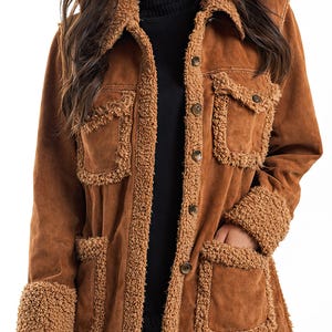 May include: Brown suede jacket with a sherpa trim around the collar, cuffs, and pockets. The jacket has a button-up front and two chest pockets. A stylish outerwear piece for fall and winter.