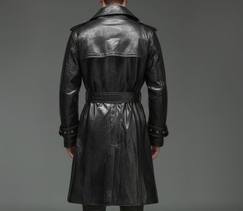 May include: A black leather trench coat featuring a wide collar, shoulder epaulets, and a belted waist. The coat has long sleeves with buckled cuffs and a back storm flap, extending to a mid-calf length with a clean, polished finish.