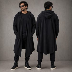 May include: A long-length black hooded cardigan featuring an open front design, long sleeves, and a relaxed fit. The garment is paired with matching black trousers and black trainers, showcasing a solid black colour palette throughout the outfit.