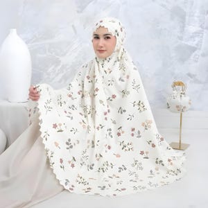 May include: A cream-coloured prayer garment featuring a delicate floral pattern with small brown, pink, and green flowers and leaves. The head covering has a scalloped edge detail, and the set includes a matching small drawstring pouch.