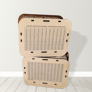 May include: Two wooden coin banks with a grid of numbers and the phrase "Let the coins accumulate, and dreams come true!" printed on them. The banks are made of light brown wood and have a slot for inserting coins.