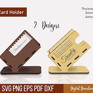 May include: Two wooden card holders in brown and tan, each with a unique design. The brown holder displays a card with the "Trendiii Treasures" logo. The tan holder has a different cutout design. The text "Card Holder" and "2 Designs" are visible.