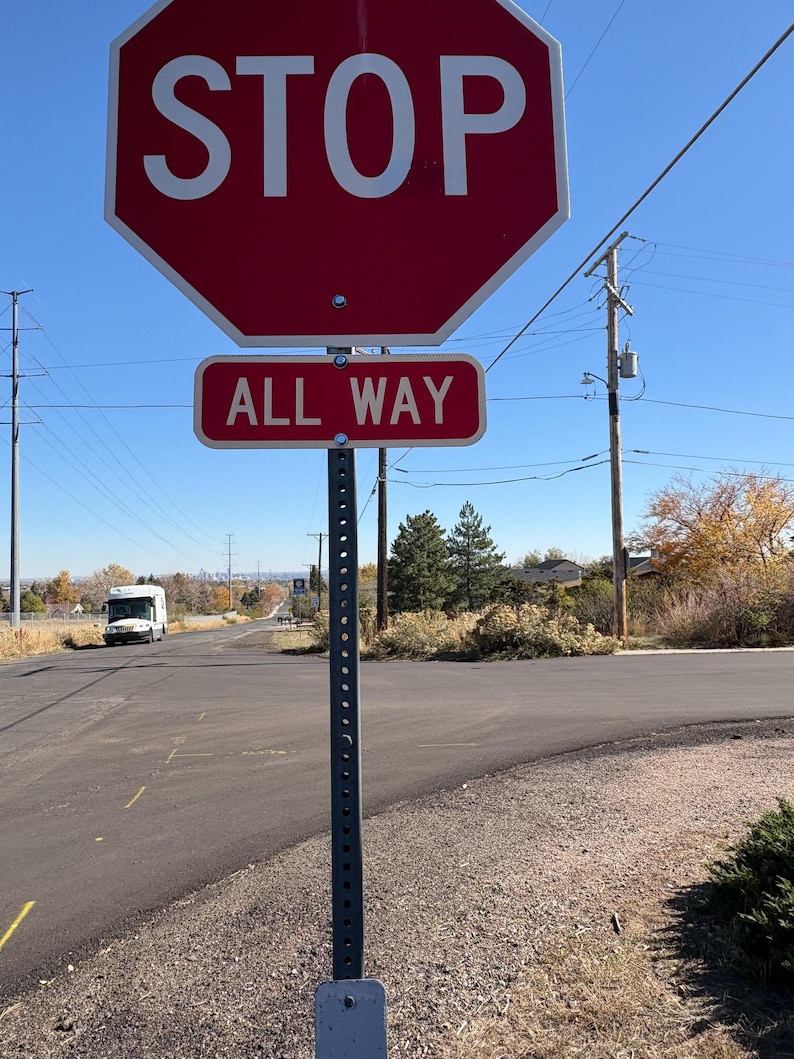 Peut inclure: Un panneau STOP octogonal rouge avec texte blanc et un panneau rectangulaire ALL WAY en dessous. Les panneaux sont mont&eacute;s sur un poteau m&eacute;tallique, avec une route et un ciel bleu en arri&egrave;re-plan.