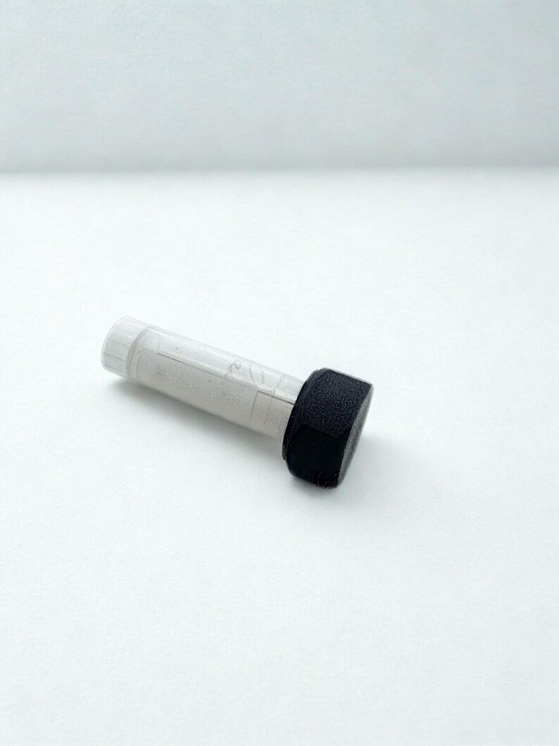 Peut inclure: Une bouteille cylindrique transparente avec un bouchon blanc et un applicateur &eacute;ponge noir et rectangulaire. La bouteille contient un liquide gris clair. L'applicateur est fix&eacute; &agrave; l'extr&eacute;mit&eacute; de la bouteille. L'objet est sur fond blanc.