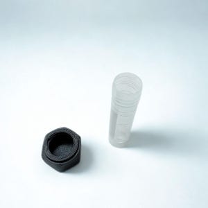 Peut inclure: Un r&eacute;cipient cylindrique transparent avec un design nervur&eacute; et un couvercle hexagonal noir s&eacute;par&eacute;. Le r&eacute;cipient est transparent et le couvercle est noir mat fonc&eacute;. Les articles sont pos&eacute;s sur un fond blanc uni.