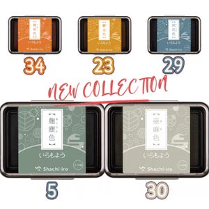 May include: A collection of five ink pads in various colors, including orange, yellow, blue, green, and gray. Each pad is rectangular with a black frame and a decorative label. The text "NEW COLLECTION" is displayed in red.