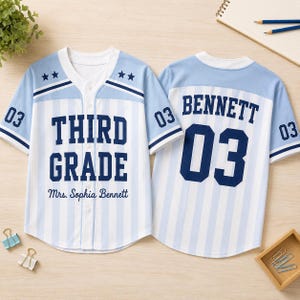May include: A light blue and white striped baseball jersey featuring the text THIRD GRADE and Mrs. Sophia Bennett on the front, with the name BENNETT and the number 03 on the back. The sleeves display the number 03 and two stars on each shoulder.
