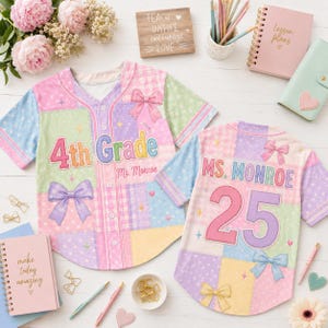 May include: Two button-down baseball jerseys featuring a pastel patchwork design of pink, blue, yellow, and green. The front displays '4th Grade' and 'Ms. Monroe', while the back shows 'MS. MONROE' and '25', all accented with bow graphics.