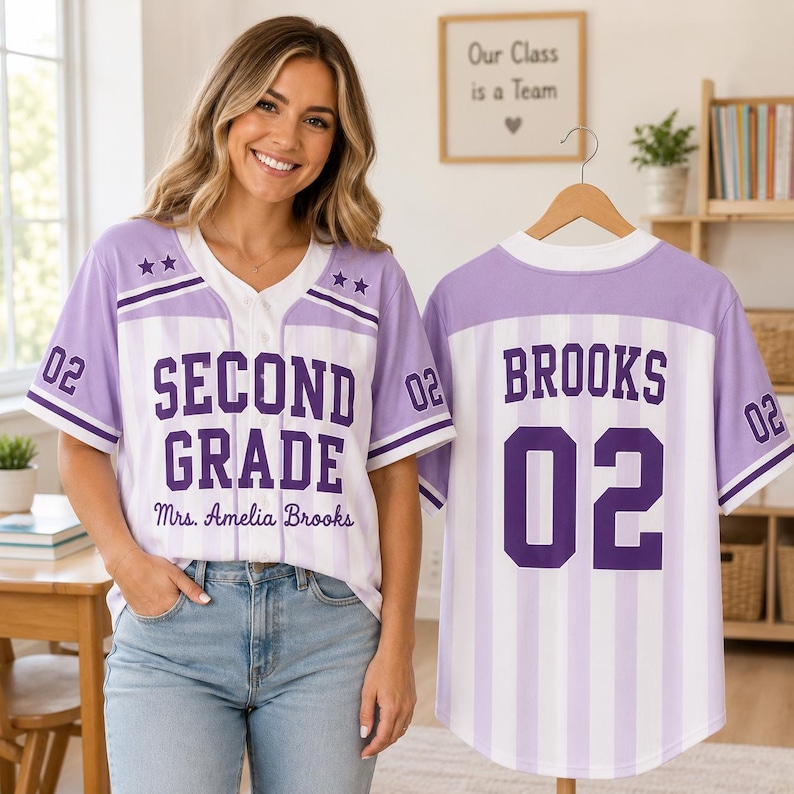 May include: A light purple and white vertical striped baseball jersey featuring the text SECOND GRADE and Mrs. Amelia Brooks on the front, with the number 02 and two stars on each sleeve. The back displays the name BROOKS and the number 02.