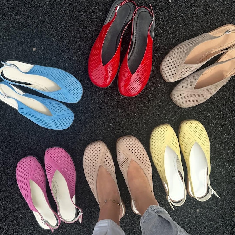 May include: A collection of colorful women's flats in various shades, including red, blue, pink, beige, and yellow. The shoes have a perforated design and slingback straps. The flats are arranged on a dark surface.