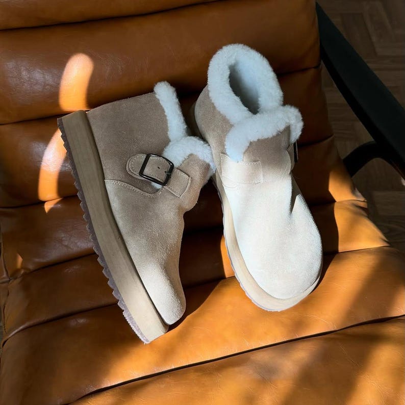 Pair of beige suede boots with white shearling fur, comfortable handmade winter footwear