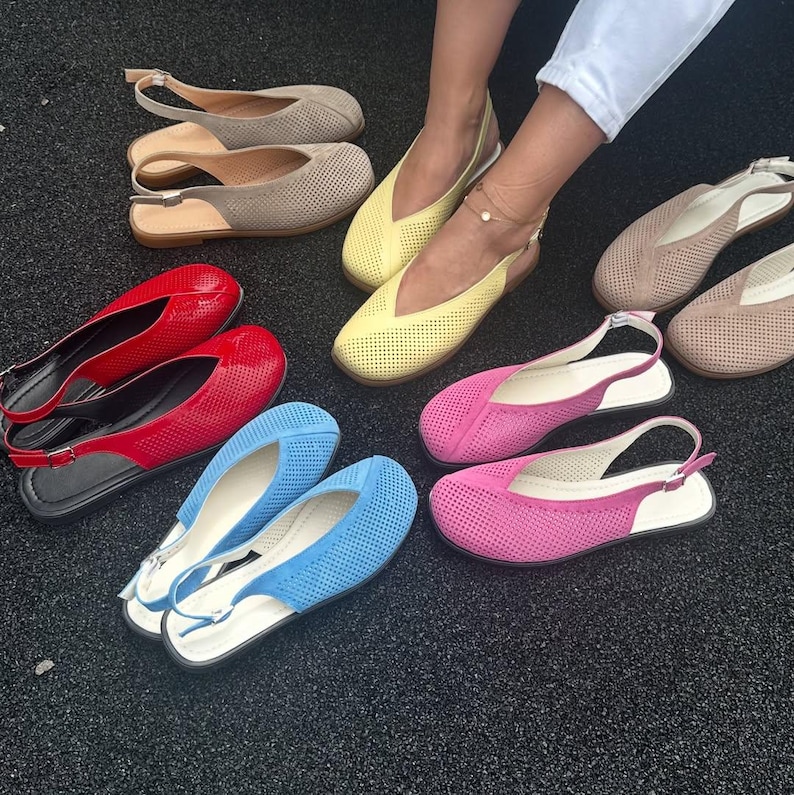 May include: A collection of colorful women's flats in various shades, including red, blue, pink, yellow, and beige. The shoes feature a perforated design and slingback straps. The flats are displayed on a dark surface.