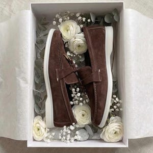 Handmade brown suede loafers in gift box with premium packaging and floral decoration.