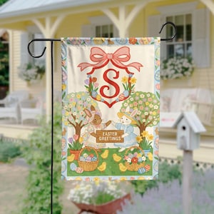 May include: A garden flag with an Easter theme. The flag features a large red letter "S" inside a floral wreath, a pink bow, and two bunnies. The words "Easter Greetings" are also visible. Baskets of eggs and chicks are also shown.
