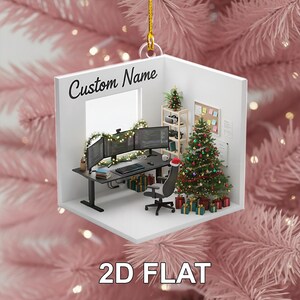 May include: A 2D flat Christmas ornament featuring a miniature office scene. The ornament includes a desk with three computer monitors, a Christmas tree, and the text "Custom Name" and "2D FLAT". The ornament is suspended by a gold string.