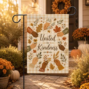 Pode incluir: Uma bandeira de jardim retangular com fundo xadrez bege e branco, apresentando o texto United in Kindness no centro. O design inclui ilustrações de várias mãos segurando folhas de outono, trigo e flores em um padrão circular.