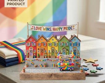 May include: A colorful Pride-themed decorative display featuring five houses painted in rainbow colors. A banner reads "LOVE WINS: HAPPY PRIDE." A miniature parade float and flags add to the festive scene. The words "2D FLAT PRINTED PRODUCT" are in the upper left corner.