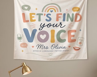 May include: A cream-colored wall tapestry featuring the text "LET'S FIND your VOICE" in colorful, rounded letters. It includes a rainbow, speech bubbles, a microphone, a card with "Aa" and an apple, and the name "Mrs. Olivia" with "SPEECH-LANGUAGE PATHOLOGIST" printed below.