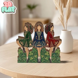 May include: Wooden decorative piece featuring three Irish dancers in traditional dresses of green, blue, and red. The dancers are set against a backdrop of shamrocks and Celtic knot designs. The piece has the text "2D FLAT" in the upper left corner.