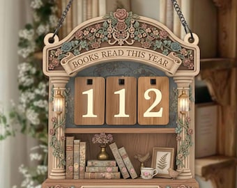 May include: Wooden wall hanging with the text "BOOKS READ THIS YEAR" and the number "112". The decorative piece features a shelf with miniature books, a vase, a teacup, and the text "MISA'S LIBRARY". It is adorned with floral and scrollwork details.