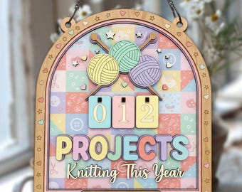 May include: Wooden knitting project log sign with a pastel color scheme. The sign features three yarn balls, knitting needles, and the words "012 PROJECTS Knitting This Year." The sign is personalized with "Sophie's Knitting Log."